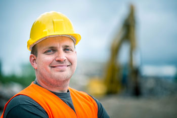 Coal worker standing in front of a large piece of machinery with the background blurred